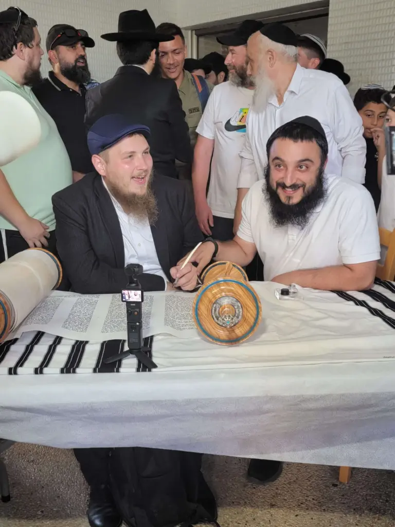 a stam sofer guiding a participant in torah scroll writing, filling in the final letters of a new torah scroll. This event highlights the dedication required to create kosher holidays items megillat esther and tefillin torah