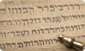 Faded Hebrew letters on an aging Torah scroll requiring inspection